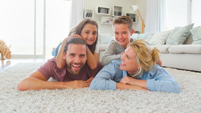 A family smiling while laying down on a clean carpet
